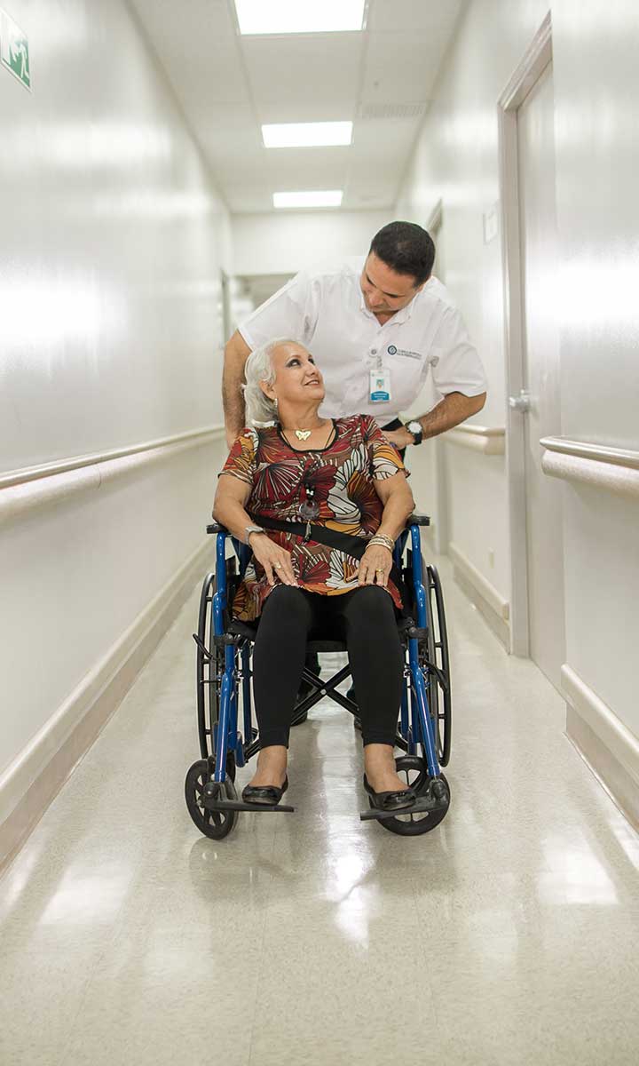 Trabajador de un hospital lleva a un paciente en silla de ruedas